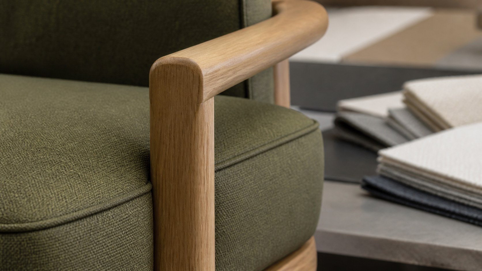 Close detail of olive performance upholstery, sealed seam and rounded oak arm